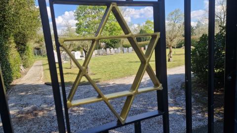 Gouden davidster in het toegangshek van de Joodse Begraafplaats in Hilversum, met uitzicht op de graven.