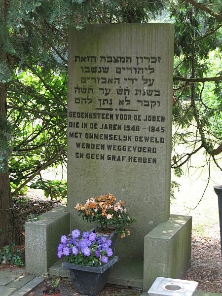 Herdenkingsmonument met Hebreeuwse en Nederlandse tekst op de Joodse Begraafplaats in Hilversum, met bloemen aan de voet.